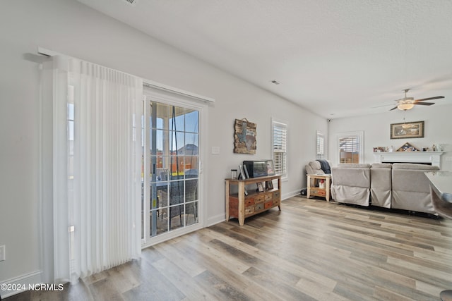 interior space featuring light hardwood / wood-style flooring, a wealth of natural light, ceiling fan, and a fireplace