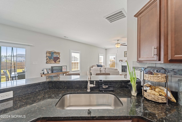 kitchen featuring dark stone countertops, ceiling fan, tasteful backsplash, and sink