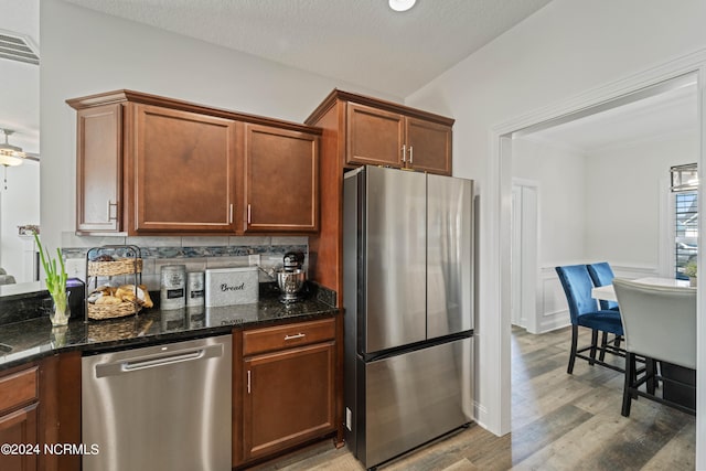 kitchen with ceiling fan, a textured ceiling, backsplash, stainless steel appliances, and hardwood / wood-style floors