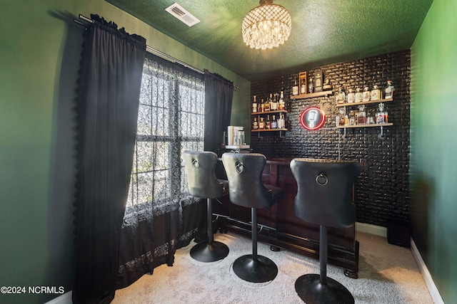 bar featuring an inviting chandelier, a textured ceiling, brick wall, and carpet floors