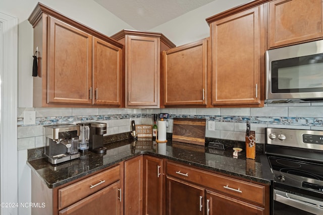 kitchen featuring a textured ceiling, appliances with stainless steel finishes, backsplash, and dark stone counters