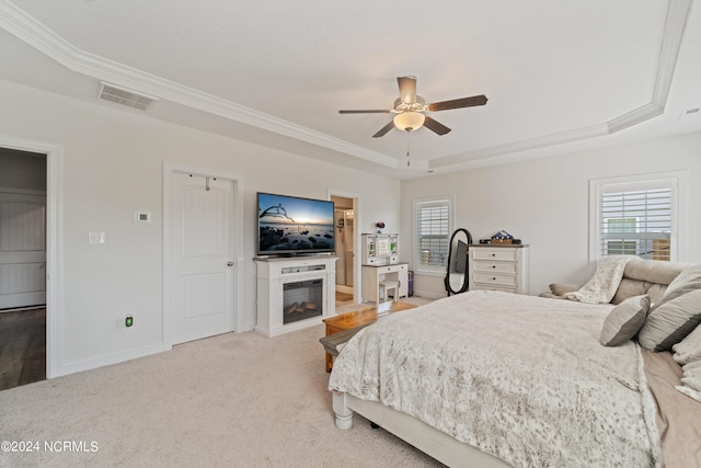 bedroom featuring a raised ceiling, carpet flooring, ornamental molding, and ceiling fan