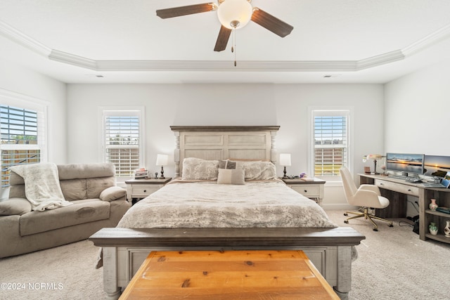 carpeted bedroom with multiple windows, a tray ceiling, ornamental molding, and ceiling fan