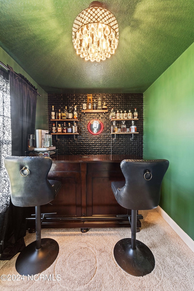 bar with a textured ceiling, a chandelier, and carpet flooring