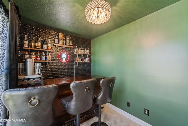 bar with carpet floors, a textured ceiling, and a chandelier