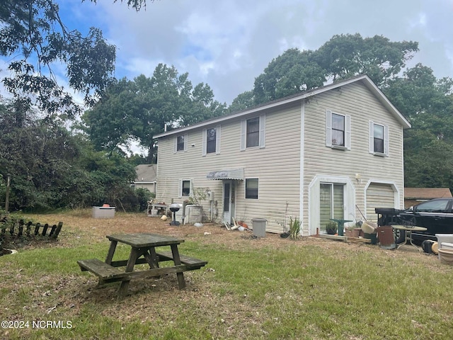 back of house featuring a garage and a lawn