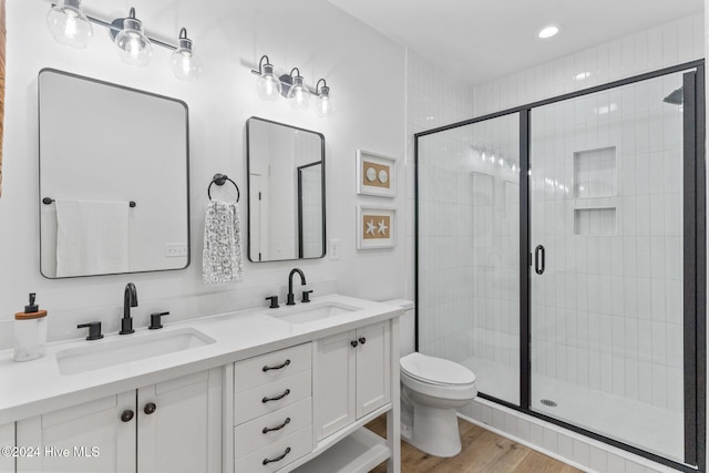 bathroom with vanity, hardwood / wood-style floors, a shower with shower door, and toilet