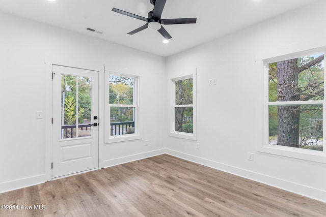 empty room featuring ceiling fan, a wealth of natural light, and light wood-type flooring