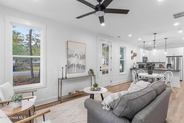 living room with light hardwood / wood-style flooring, a healthy amount of sunlight, and ceiling fan