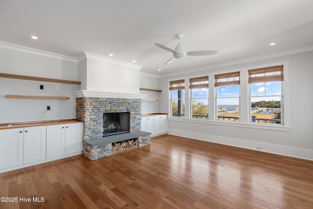 unfurnished living room featuring hardwood / wood-style floors, a fireplace, ornamental molding, and ceiling fan