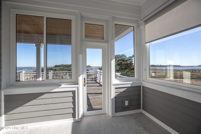 unfurnished sunroom featuring a water view