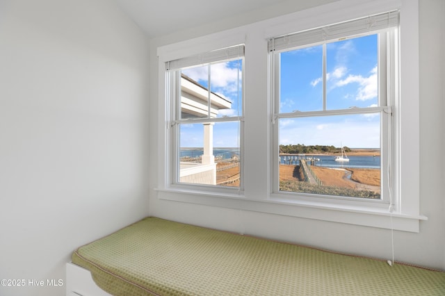 unfurnished bedroom featuring multiple windows, vaulted ceiling, and a water view