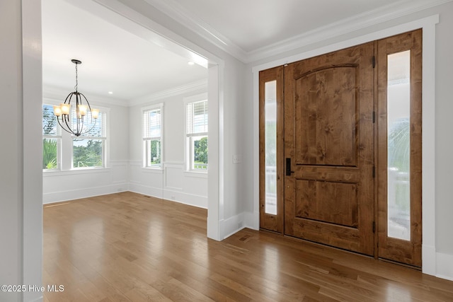 foyer entrance featuring an inviting chandelier, ornamental molding, and light wood-type flooring