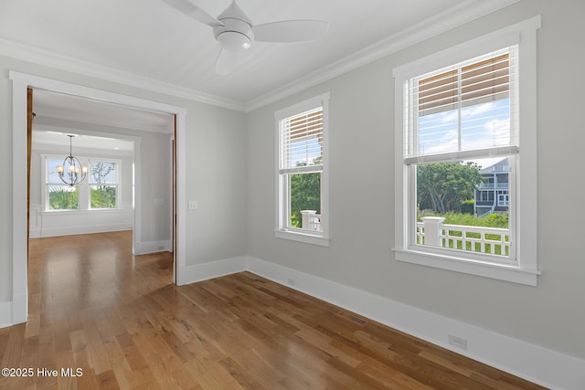 unfurnished room with hardwood / wood-style floors, ceiling fan with notable chandelier, and ornamental molding