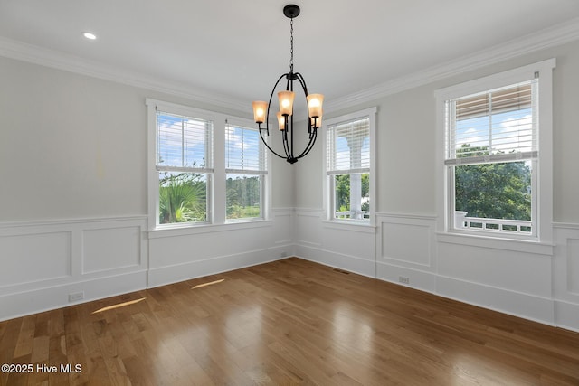 unfurnished dining area featuring an inviting chandelier, plenty of natural light, and crown molding