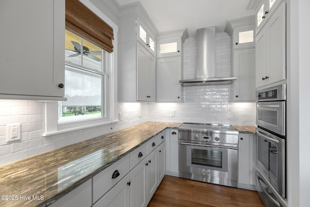 kitchen with stainless steel appliances, white cabinets, and wall chimney exhaust hood