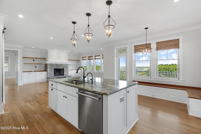 kitchen with decorative light fixtures, sink, dark stone countertops, a kitchen island with sink, and stainless steel dishwasher