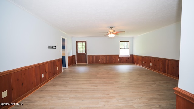 spare room featuring wood walls, ceiling fan, and light hardwood / wood-style flooring