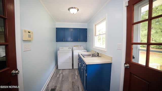 clothes washing area featuring sink, cabinets, hardwood / wood-style flooring, washing machine and dryer, and a healthy amount of sunlight