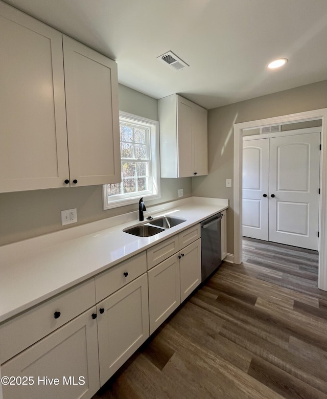 kitchen featuring visible vents, dark wood-style floors, stainless steel dishwasher, white cabinetry, and a sink