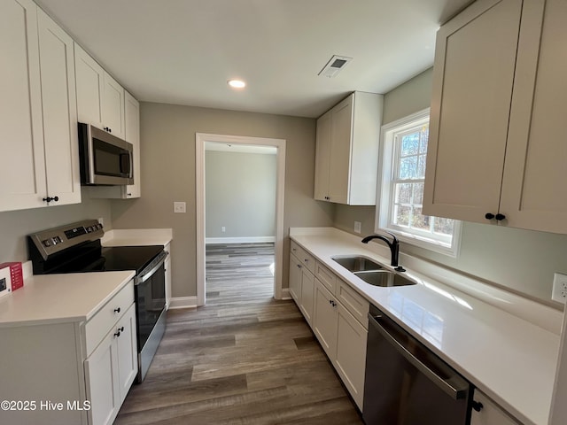 kitchen featuring stainless steel appliances, light countertops, a sink, and visible vents