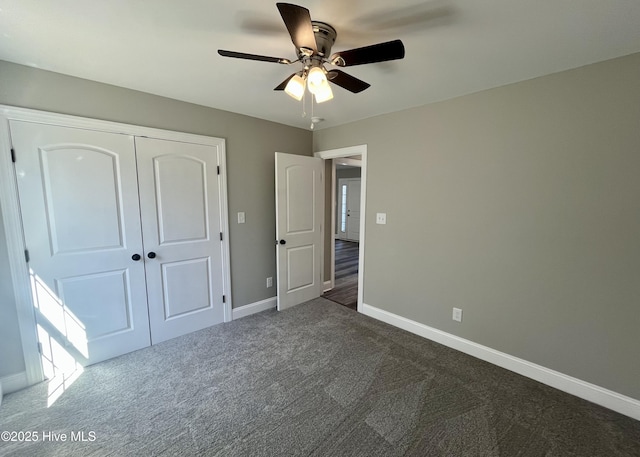 unfurnished bedroom with a ceiling fan, baseboards, dark carpet, and a closet