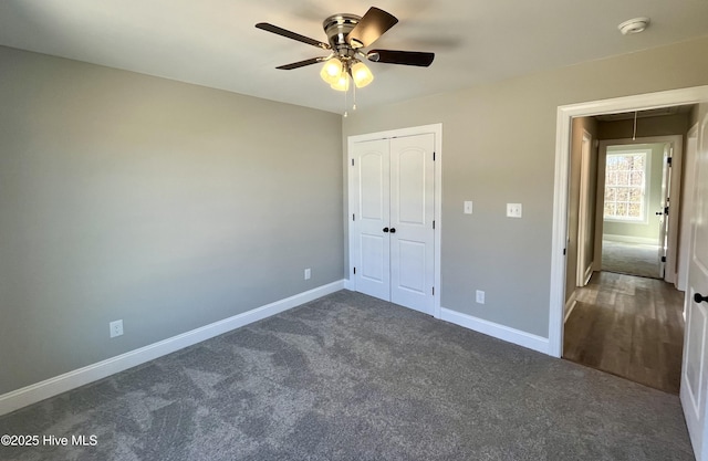 unfurnished bedroom with carpet flooring, a ceiling fan, baseboards, a closet, and attic access