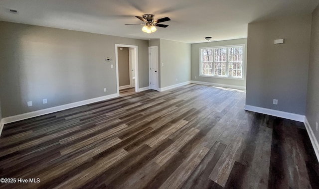 spare room featuring a ceiling fan, visible vents, baseboards, and dark wood-type flooring