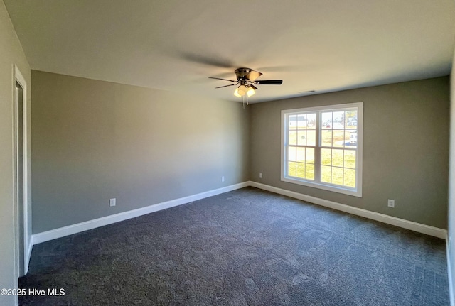 spare room featuring visible vents, baseboards, dark colored carpet, and a ceiling fan