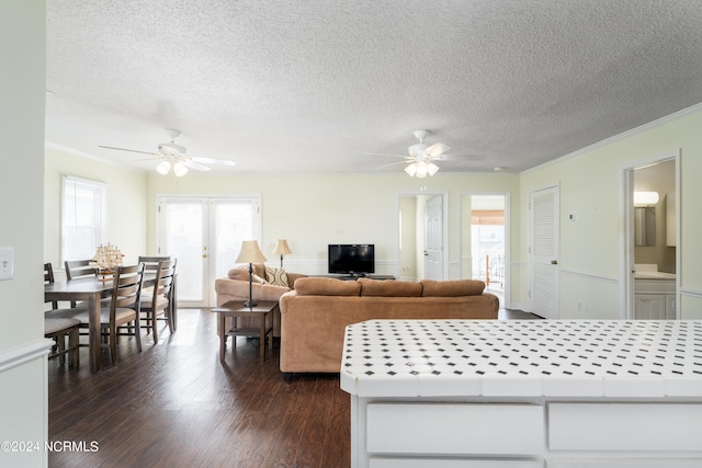 living room featuring ornamental molding, ceiling fan, dark hardwood / wood-style floors, and a textured ceiling