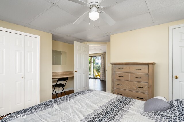 bedroom featuring ceiling fan, a closet, a paneled ceiling, and hardwood / wood-style floors