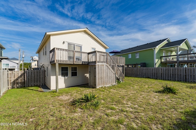 rear view of house with a lawn and a wooden deck