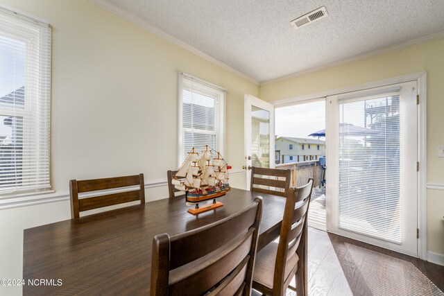 dining space with a wealth of natural light, a textured ceiling, and hardwood / wood-style flooring