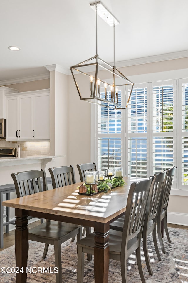 dining space featuring wood-type flooring, crown molding, a chandelier, and a healthy amount of sunlight