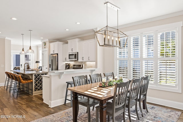 dining room featuring plenty of natural light, dark hardwood / wood-style floors, crown molding, and an inviting chandelier