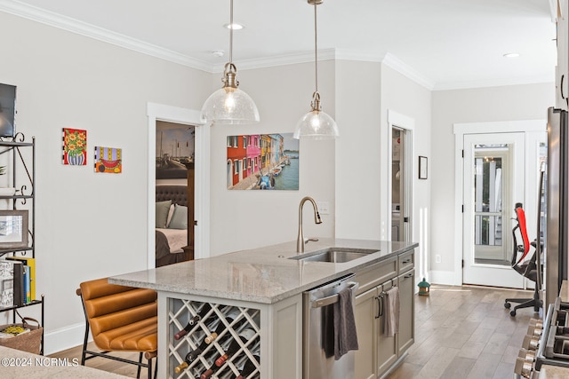 kitchen with appliances with stainless steel finishes, sink, hanging light fixtures, light hardwood / wood-style floors, and a center island with sink