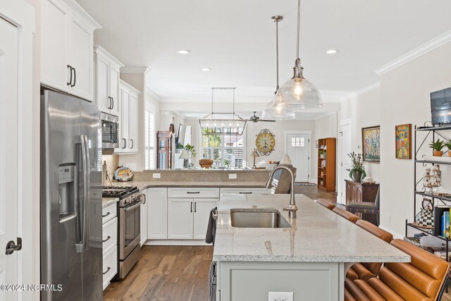 kitchen with appliances with stainless steel finishes, hardwood / wood-style floors, sink, and white cabinets