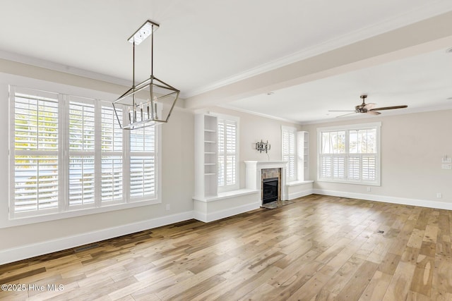 unfurnished living room featuring crown molding, a high end fireplace, light hardwood / wood-style floors, and ceiling fan with notable chandelier