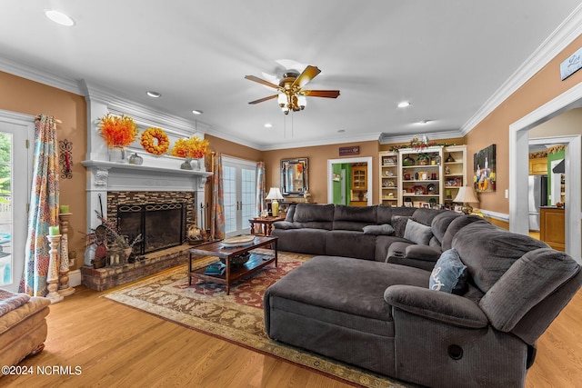 living room featuring french doors, crown molding, a stone fireplace, and wood finished floors