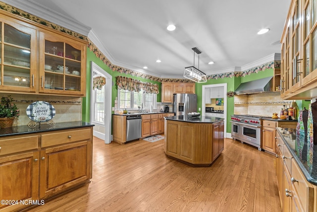 kitchen with stainless steel appliances, crown molding, light wood finished floors, and wall chimney exhaust hood