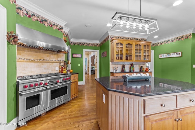 kitchen featuring range with two ovens, glass insert cabinets, ornamental molding, wall chimney range hood, and light wood-type flooring