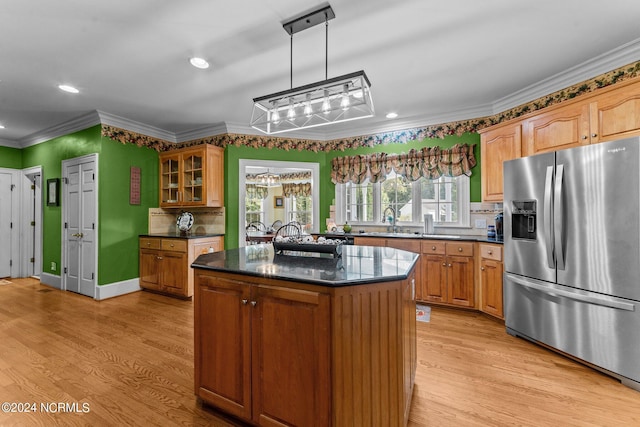 kitchen featuring glass insert cabinets, stainless steel fridge, a sink, and light wood finished floors