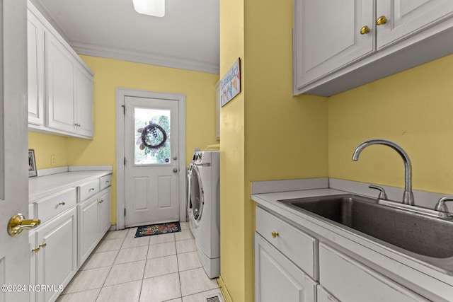 laundry room featuring light tile patterned floors, a sink, ornamental molding, cabinet space, and washer / clothes dryer