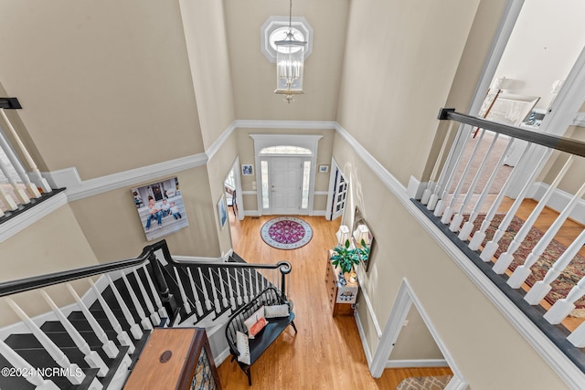 foyer featuring a towering ceiling, an inviting chandelier, stairs, and wood finished floors