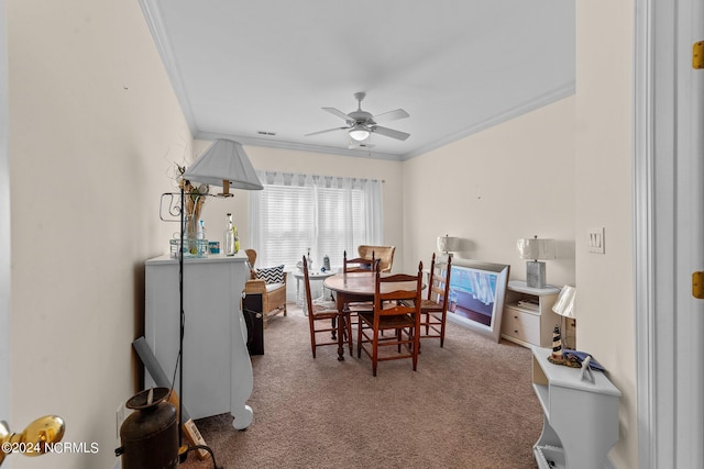 carpeted dining room featuring ornamental molding and a ceiling fan