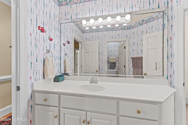 bathroom with baseboards, vanity, and wallpapered walls