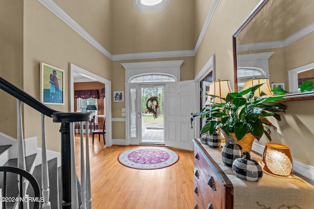 foyer featuring a towering ceiling, light wood-style floors, and stairs