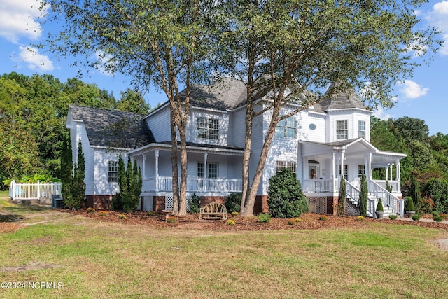 victorian house featuring a porch, a front lawn, and central air condition unit