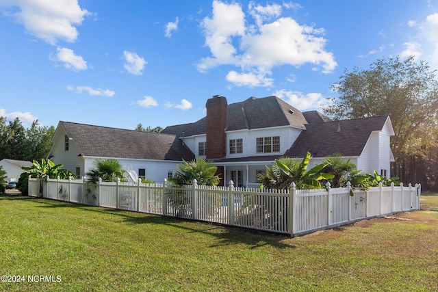 back of house with a chimney, fence, and a yard