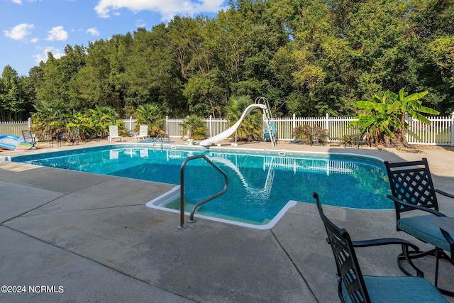 view of pool featuring a fenced in pool, fence, a water slide, and a patio